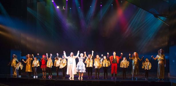 Eine Gruppe von Darstellern steht auf einer Bühne und hält sich an den Händen.