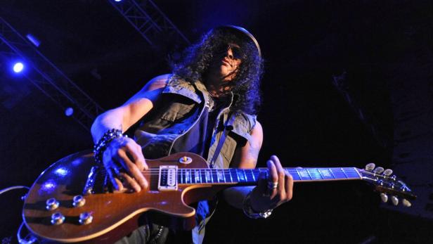 Slash spielt Gitarre während eines Konzerts.