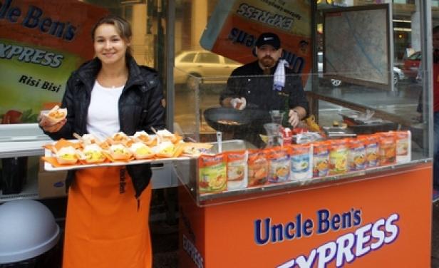 Eine Frau präsentiert Reisgerichte von „Uncle Ben's Express“ an einem Verkaufsstand.