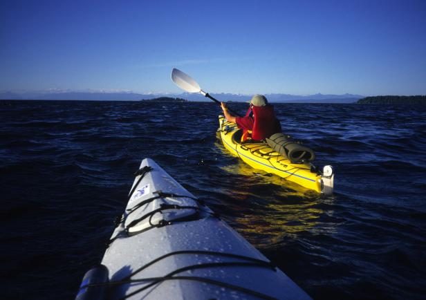 Eine Person paddelt in einem gelben Kajak auf dem offenen Meer.