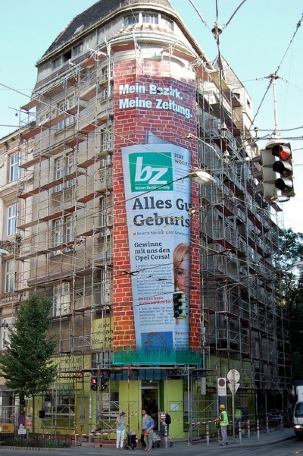 Die große Botschaft auf großer Fläche der regionalen Gratiszeitung (c: bz) Ein Gebäude ist mit einem Gerüst und einer großen Werbung für die „Wiener Bezirkszeitung“ verhüllt.