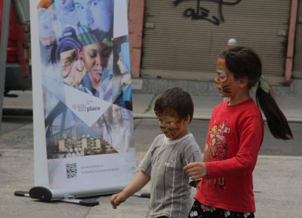 Zwei Kinder mit Tigermasken stehen vor einem Werbebanner.