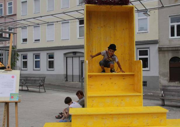 Ein Junge mit Hut klettert auf eine gelbe Holzkonstruktion.