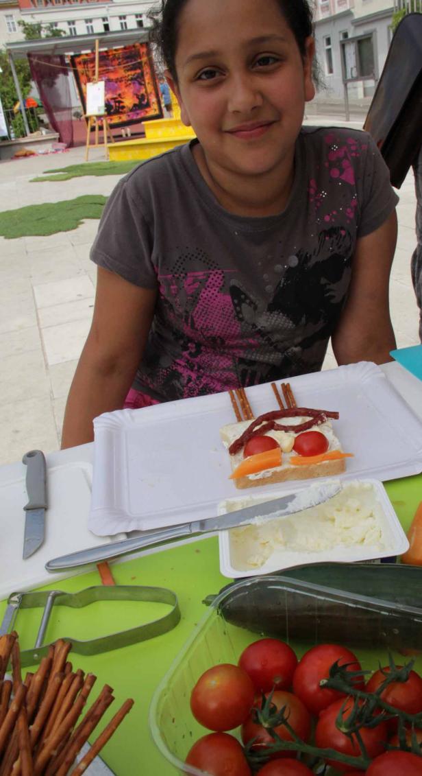 Ein Mädchen präsentiert ein Sandwich, das wie ein Gesicht verziert ist.