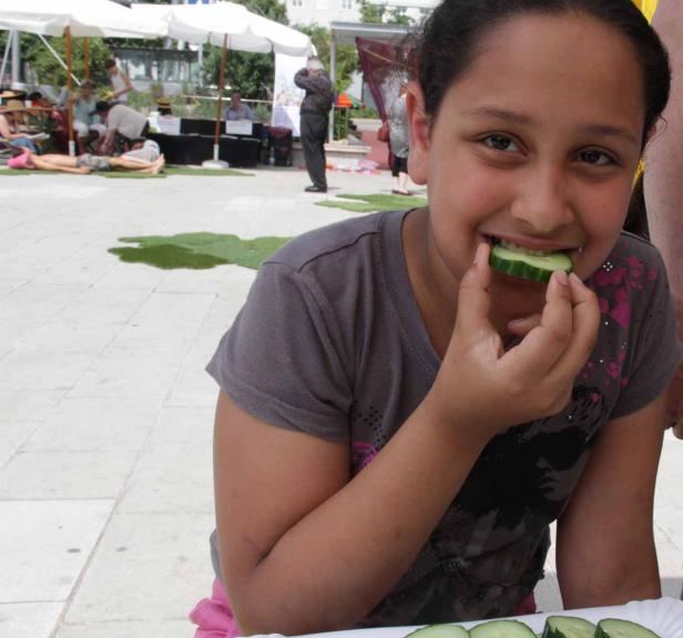 Ein junges Mädchen isst eine Gurkenscheibe.