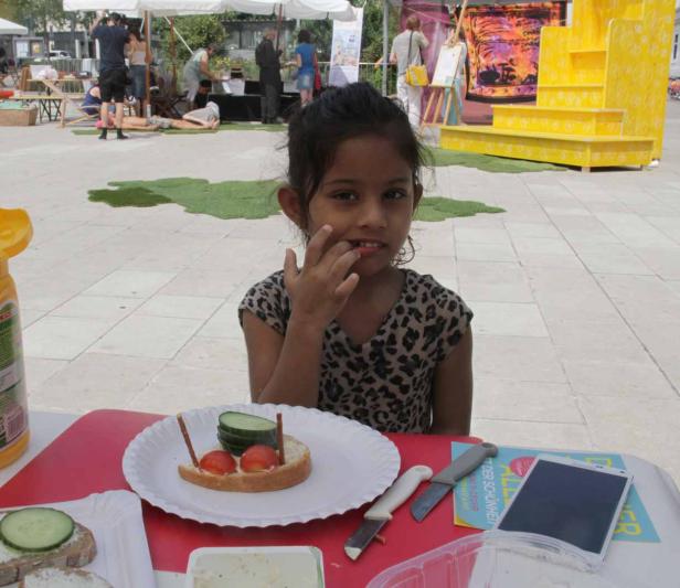 Ein junges Mädchen sitzt an einem Tisch mit einem dekorierten Brotgesicht.