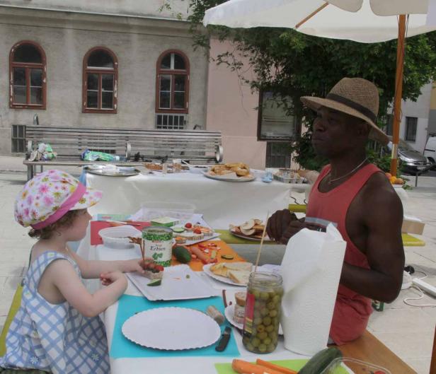Ein Mann und ein Kind sitzen an einem Tisch im Freien und bereiten eine Mahlzeit zu.