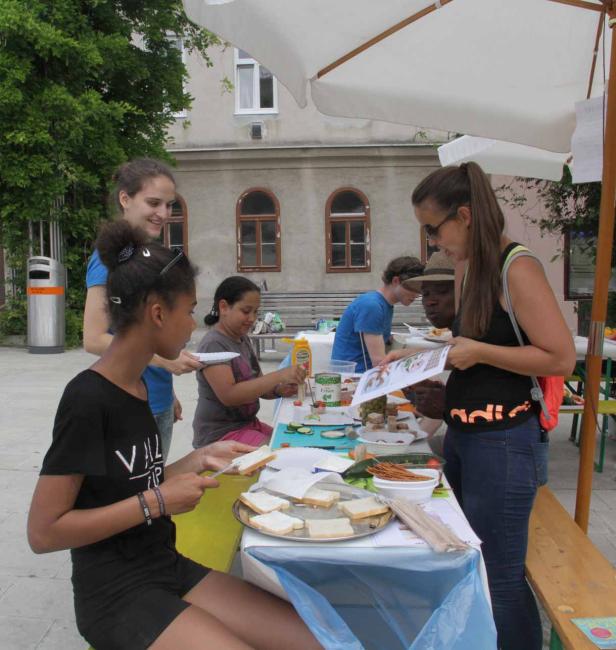 Eine Gruppe von Menschen bereitet im Freien belegte Brote zu.