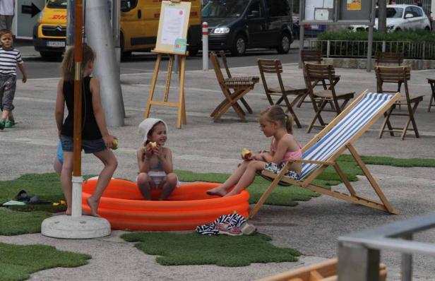 Kinder entspannen in einem Planschbecken und auf einem Liegestuhl im Freien.