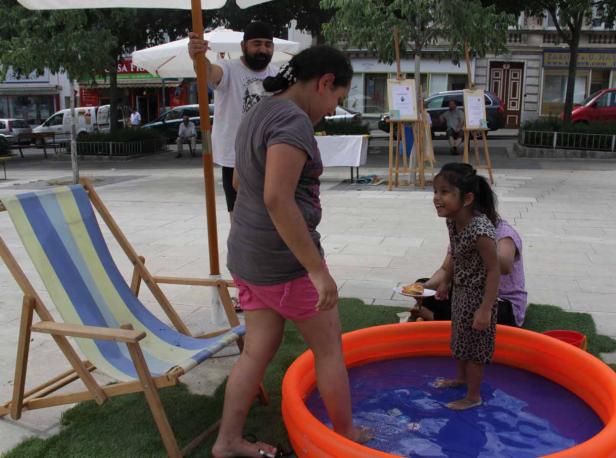 Ein Mädchen steht in einem Planschbecken auf einem öffentlichen Platz.