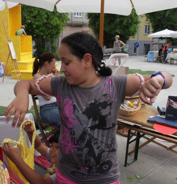 Ein Mädchen steht an einem Tisch und betrachtet ein gelbes Kleidungsstück.