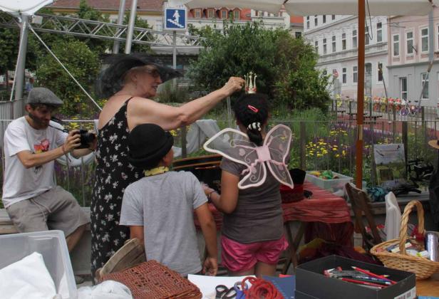 Eine Frau setzt einem Mädchen mit Feenflügeln eine Krone auf.