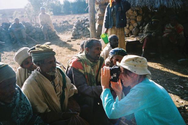 Eine Frau fotografiert eine Gruppe von Menschen in einem Dorf.