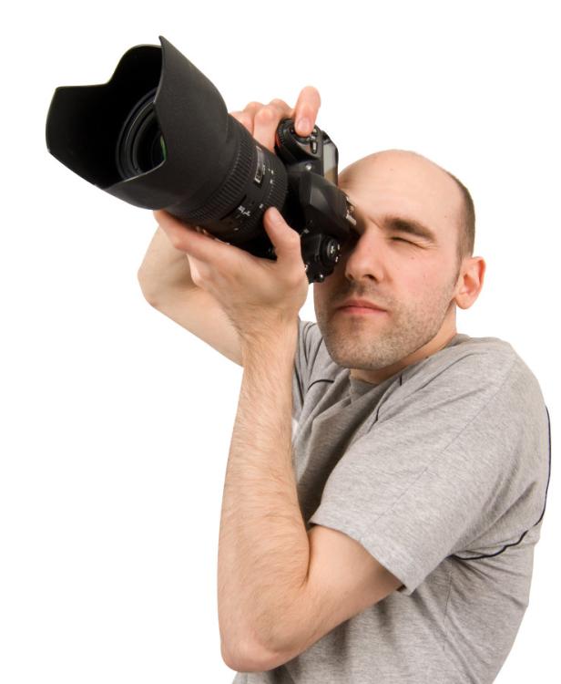 Ein Mann mit einer professionellen Kamera mit großem Objektiv vor dem Auge.