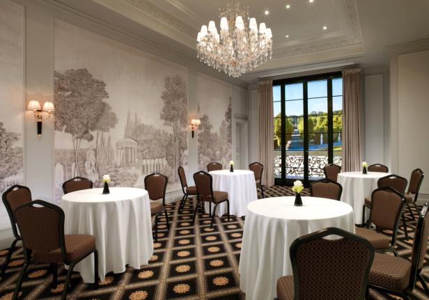 Ein eleganter Veranstaltungsraum mit runden Tischen und Blick auf einen Garten.