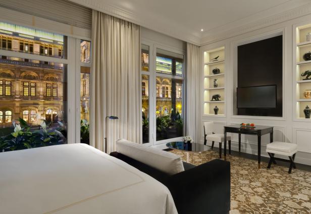 Ein Hotelzimmer mit Blick auf die beleuchtete Wiener Staatsoper.