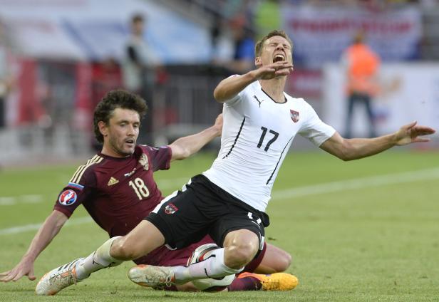 Zwei Fußballspieler kämpfen um den Ball auf dem Spielfeld.