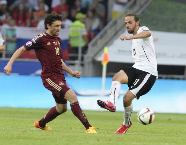 Zwei Fußballspieler kämpfen um den Ball auf dem Spielfeld.