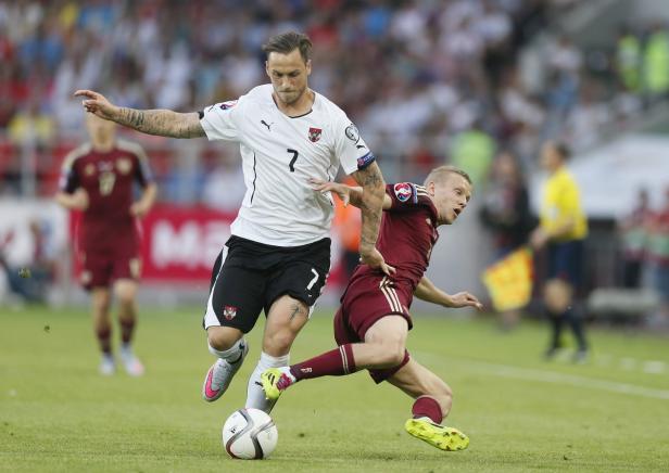 Ein österreichischer Fußballspieler kämpft um den Ball mit einem lettischen Gegenspieler.