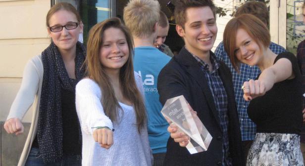 Eine Gruppe junger Leute posiert mit einer Trophäe für ein Foto.