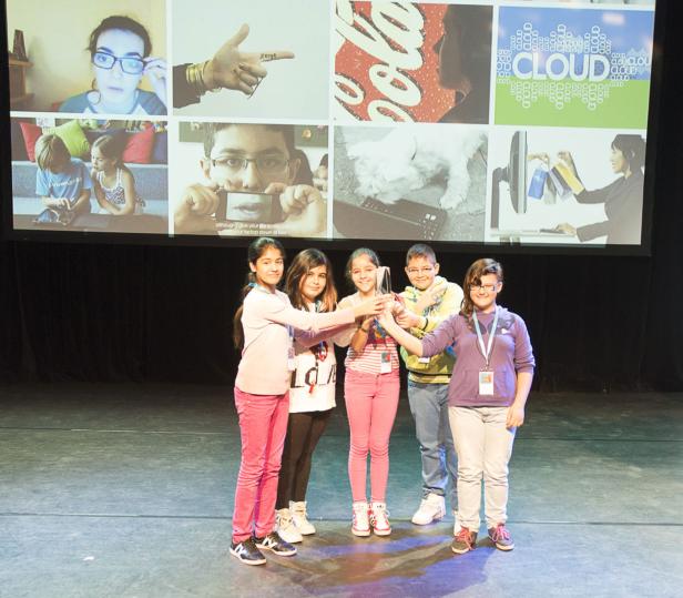 Fünf Kinder stehen auf einer Bühne und halten gemeinsam eine Trophäe hoch.