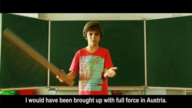 Ein Junge steht vor einer Tafel und schwingt einen Holzstab.