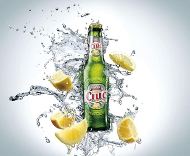 Eine Flasche Ciuc Radler ist von spritzendem Wasser und Zitronenscheiben umgeben.