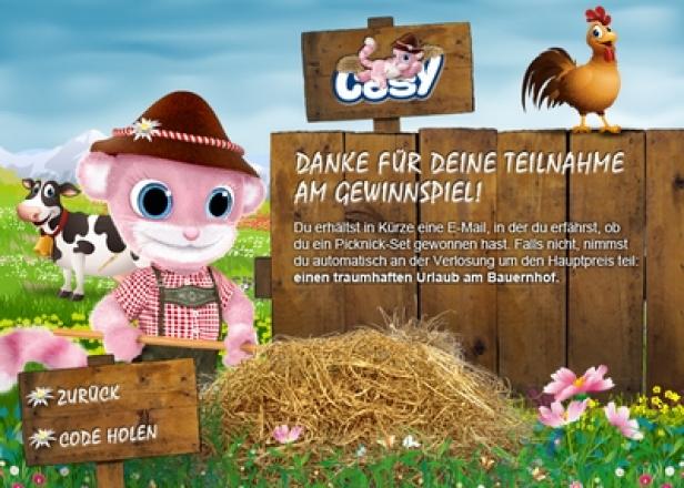 SCA Hygiene Products - Cosy-Game - Cosy.co.at - pjure isobar Ein Comic-Kätzchen im Trachtenlook vor einer ländlichen Szene mit Bauernhoftieren und einem Gewinnspiel-Hinweis.