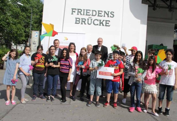 Eine Gruppe von Kindern und Erwachsenen steht vor der Friedensbrücke.