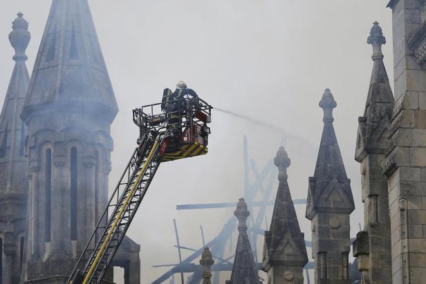 Ein Feuerwehrmann löscht ein Feuer in einem hohen Gebäude mit vielen Türmchen.