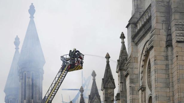 Feuerwehrleute löschen ein Feuer in einem hohen, steinernen Gebäude.