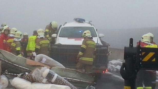 Feuerwehrleute arbeiten an einem Unfallort mit einem beschädigten Anhänger und einem Rettungswagen.