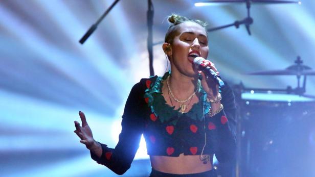 Miley Cyrus singt während eines Konzerts in ein Mikrofon.