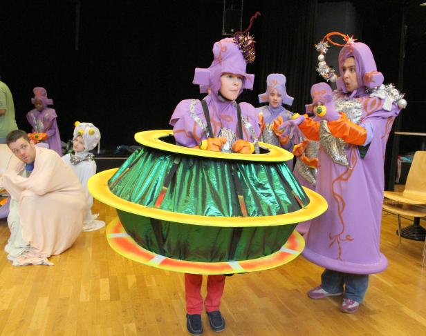 Kinder in fantasievollen Kostümen stehen auf einer Bühne.