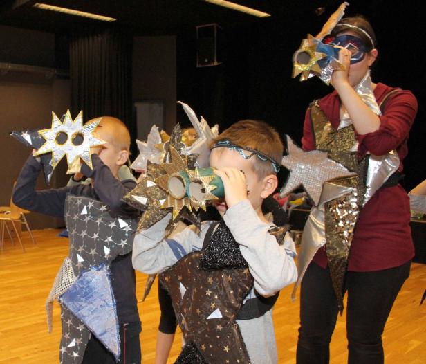 Kinder und eine Frau verkleidet mit selbstgemachten Kostümen und Sternen-Fernrohren.