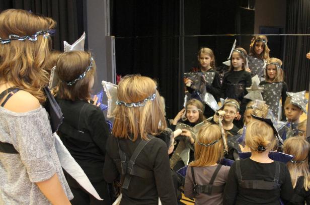 Eine Gruppe von Kindern in Sternenkostümen vor einem Spiegel.