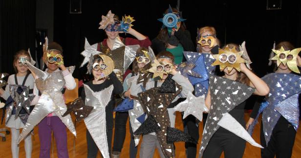 Eine Gruppe von Kindern in Sternenkostümen und Masken posiert für ein Foto.