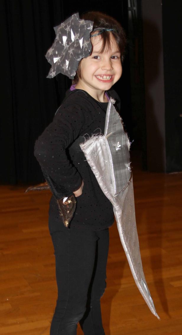 Ein lächelndes Mädchen verkleidet als Ritter mit Schwert und Schild.