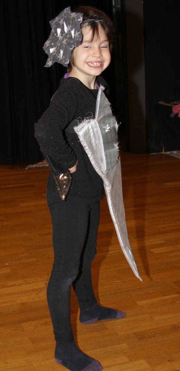 Ein lächelndes Mädchen in einem selbstgemachten Drachenkostüm.