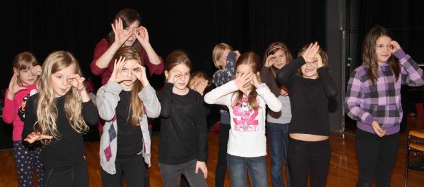 Eine Gruppe von Mädchen formt mit ihren Händen vor ihren Augen Kreise.