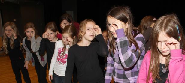 Eine Gruppe junger Mädchen steht in einer Reihe und reibt sich die Augen.