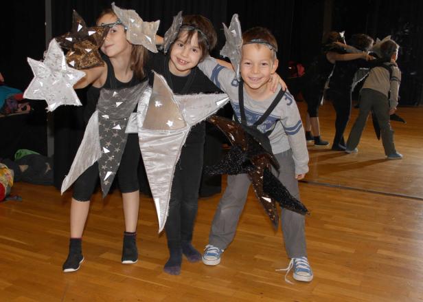 Drei Kinder in Sternenkostümen stehen auf einer Bühne.