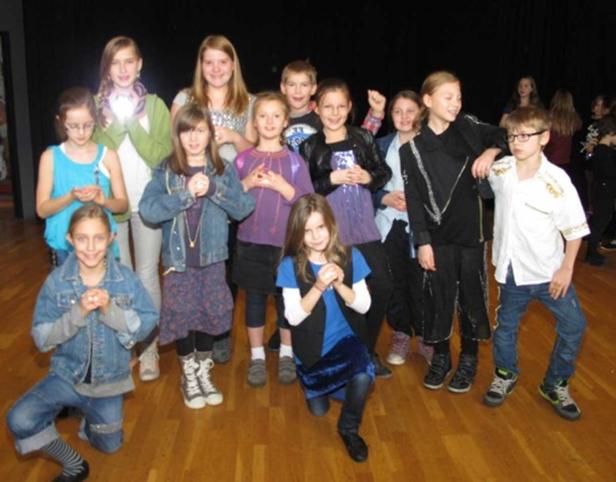 Eine Gruppe von Kindern posiert auf einer Bühne für ein Foto.