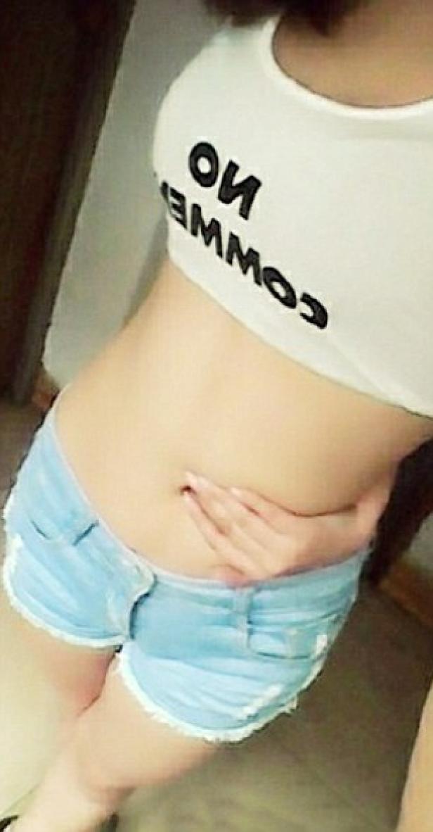 Eine Frau trägt ein bauchfreies Top mit der Aufschrift „No Comment“ und Jeansshorts.