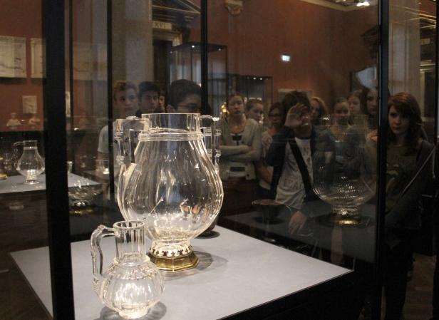 Eine Gruppe von Menschen betrachtet Glasgefäße in einem Museum.