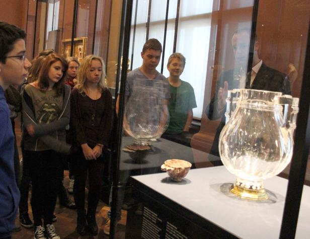 Eine Gruppe von Menschen betrachtet Glasobjekte in einem Museum.