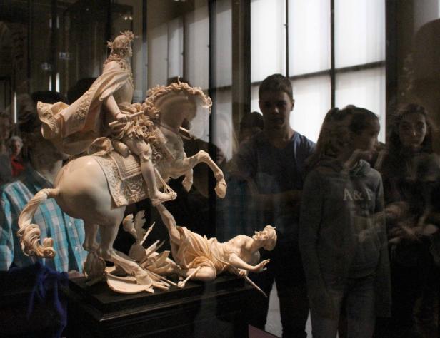 Eine Elfenbeinskulptur zeigt einen Reiter hoch zu Ross, der einen am Boden liegenden Krieger niedertritt.