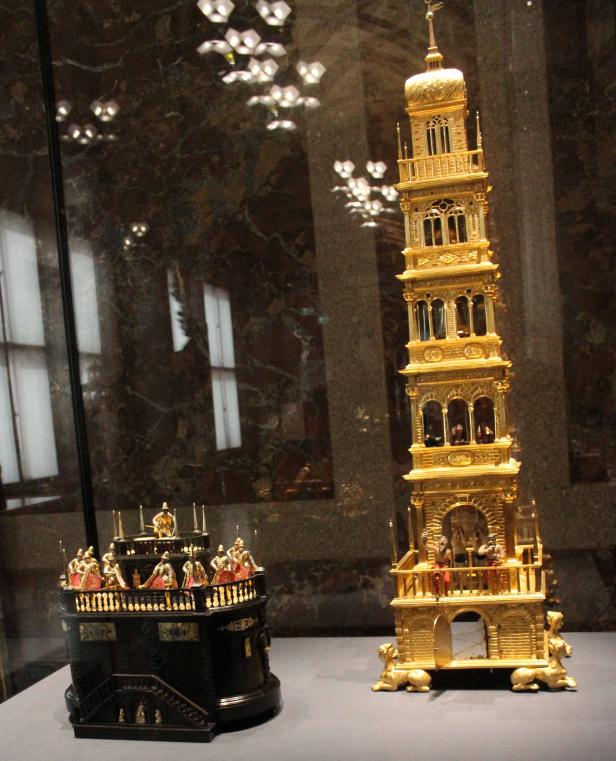 Zwei aufwendige Miniaturen, eine goldene Turmstruktur und eine dunkle Plattform mit Figuren.