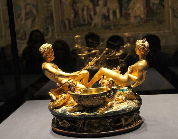 Eine goldene Skulptur von Neptun und einer Nymphe auf einem verzierten Sockel.
