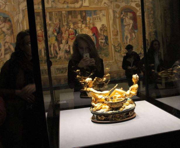 Eine goldene Skulptur von Neptun und einer Nymphe in einem Museum, fotografiert von Besuchern.